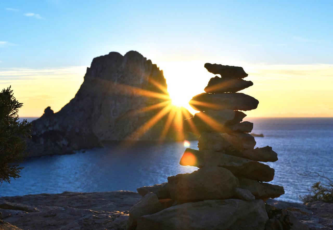 Sunset delight at Es Vedrà beach beside a manmade stack of rocks